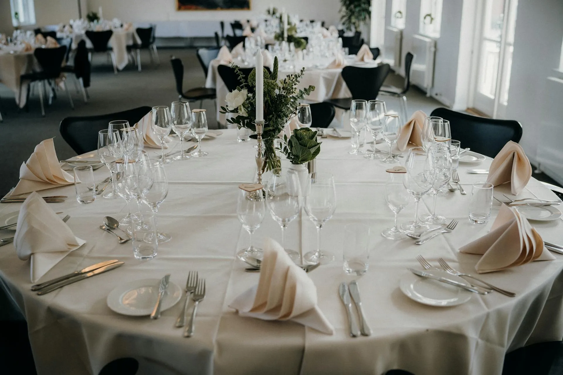 Round banquet table set with stemware, candles and floral centrepiece