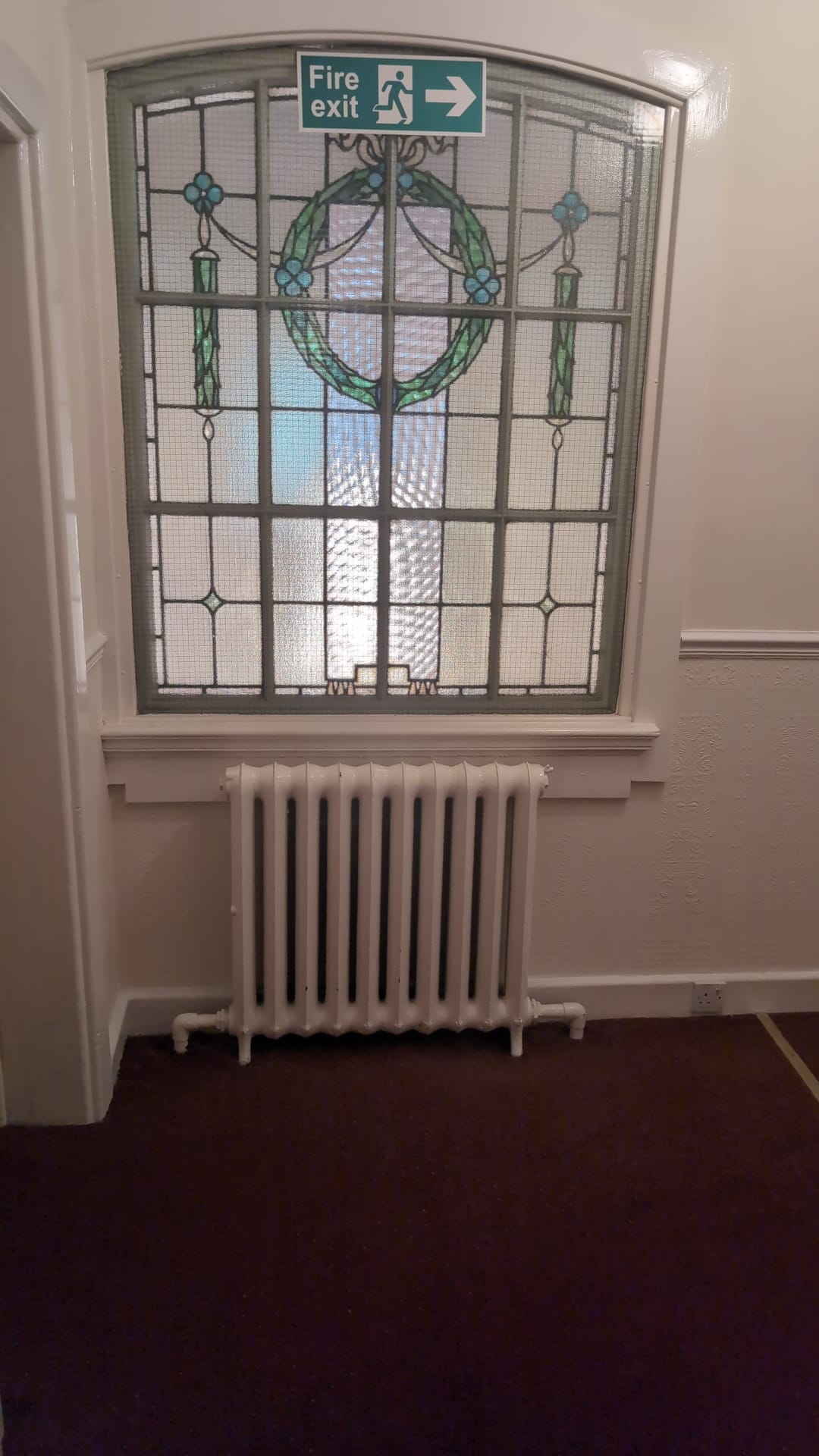 Stained glass window above a Victorian radiator