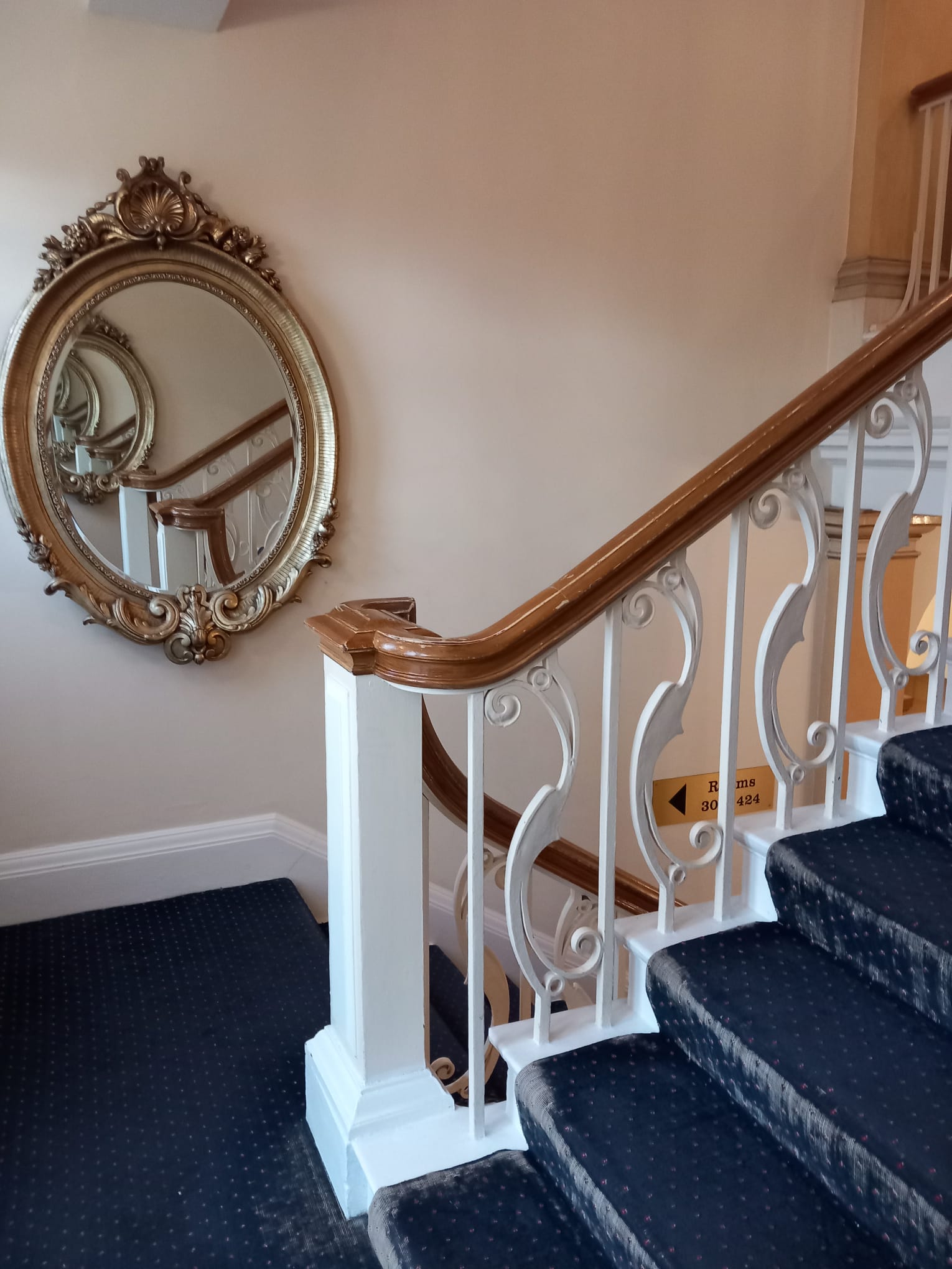 Carved staircase banister beside an ornate mirror