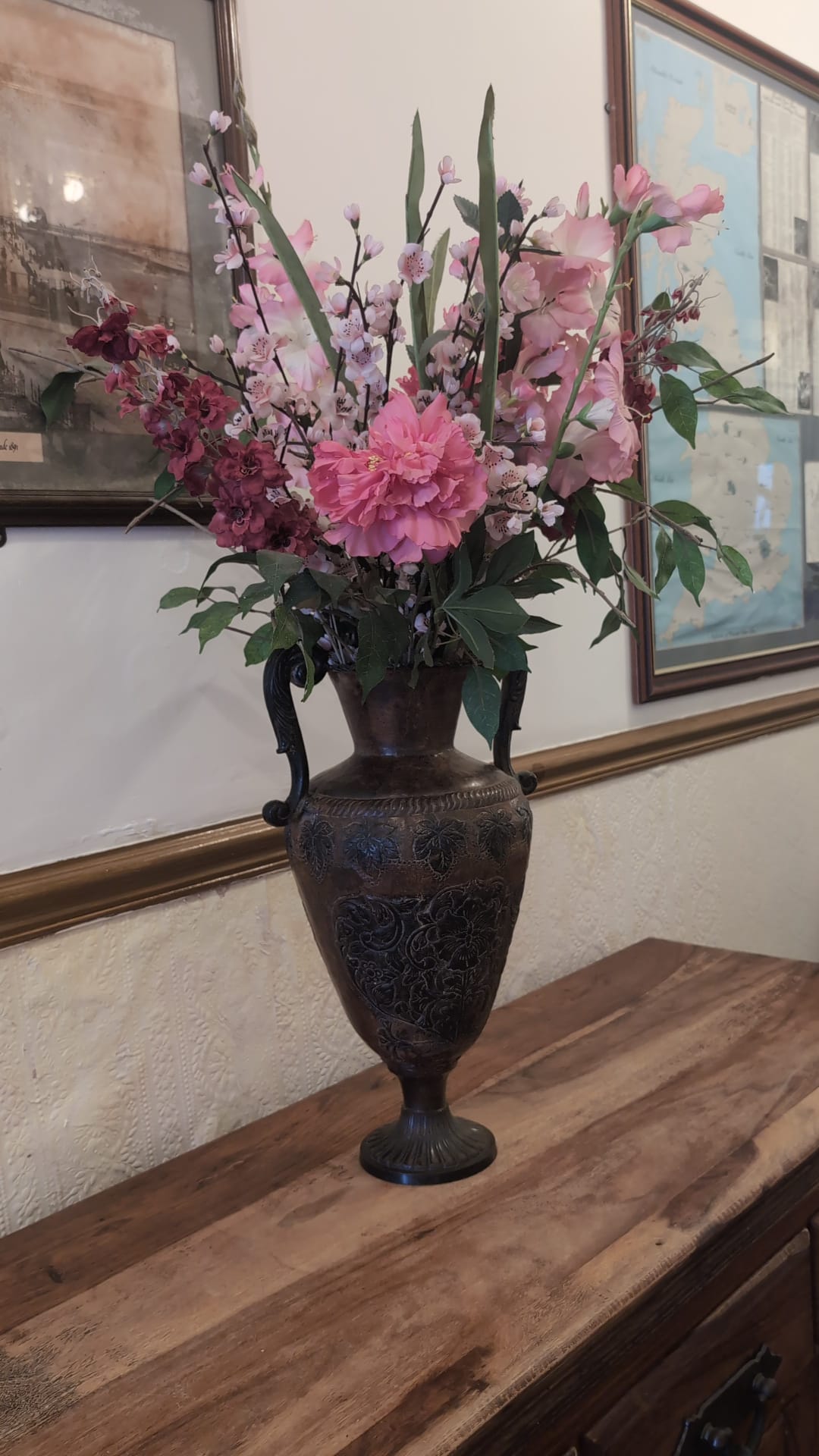Pink and burgundy flowers in an antique bronze vase in the lobby